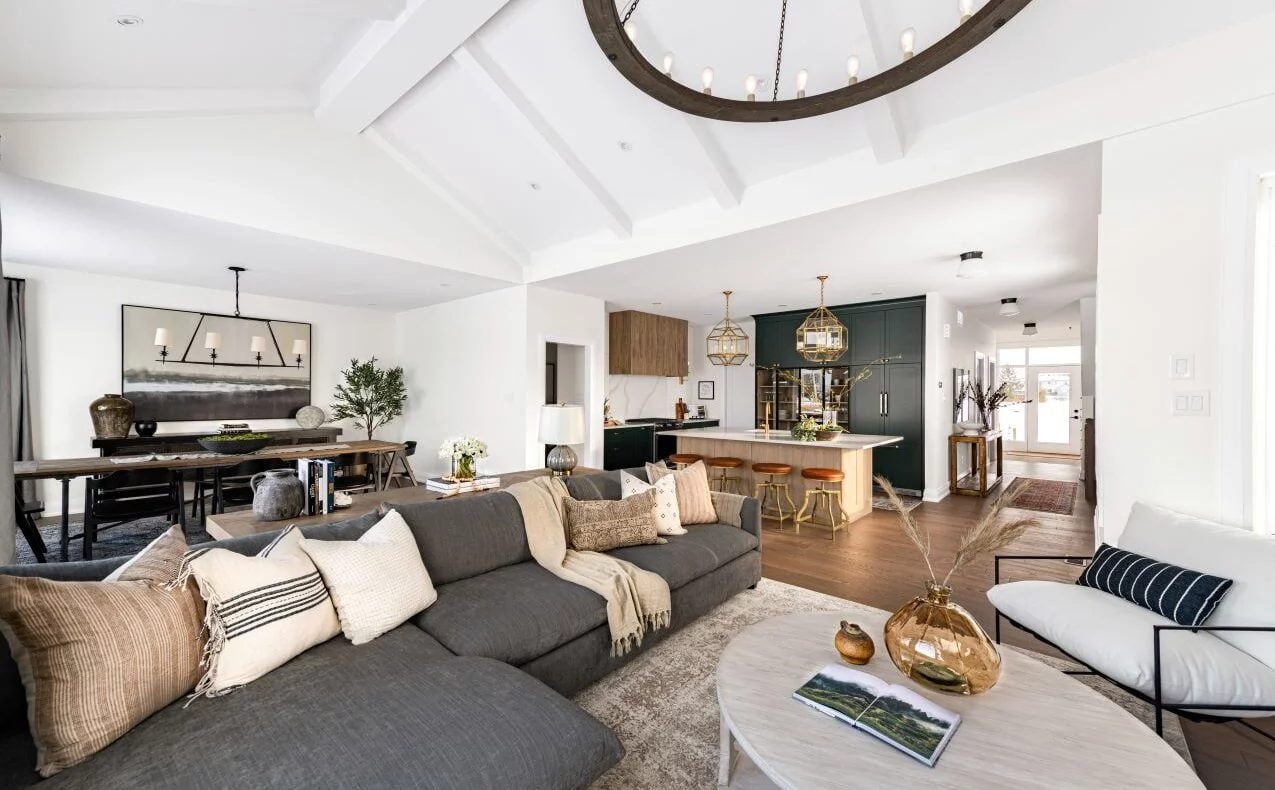 The eQ Homes Oliver living room features a spacious layout with a large couch and a stylish dining table, designed by Amsted.