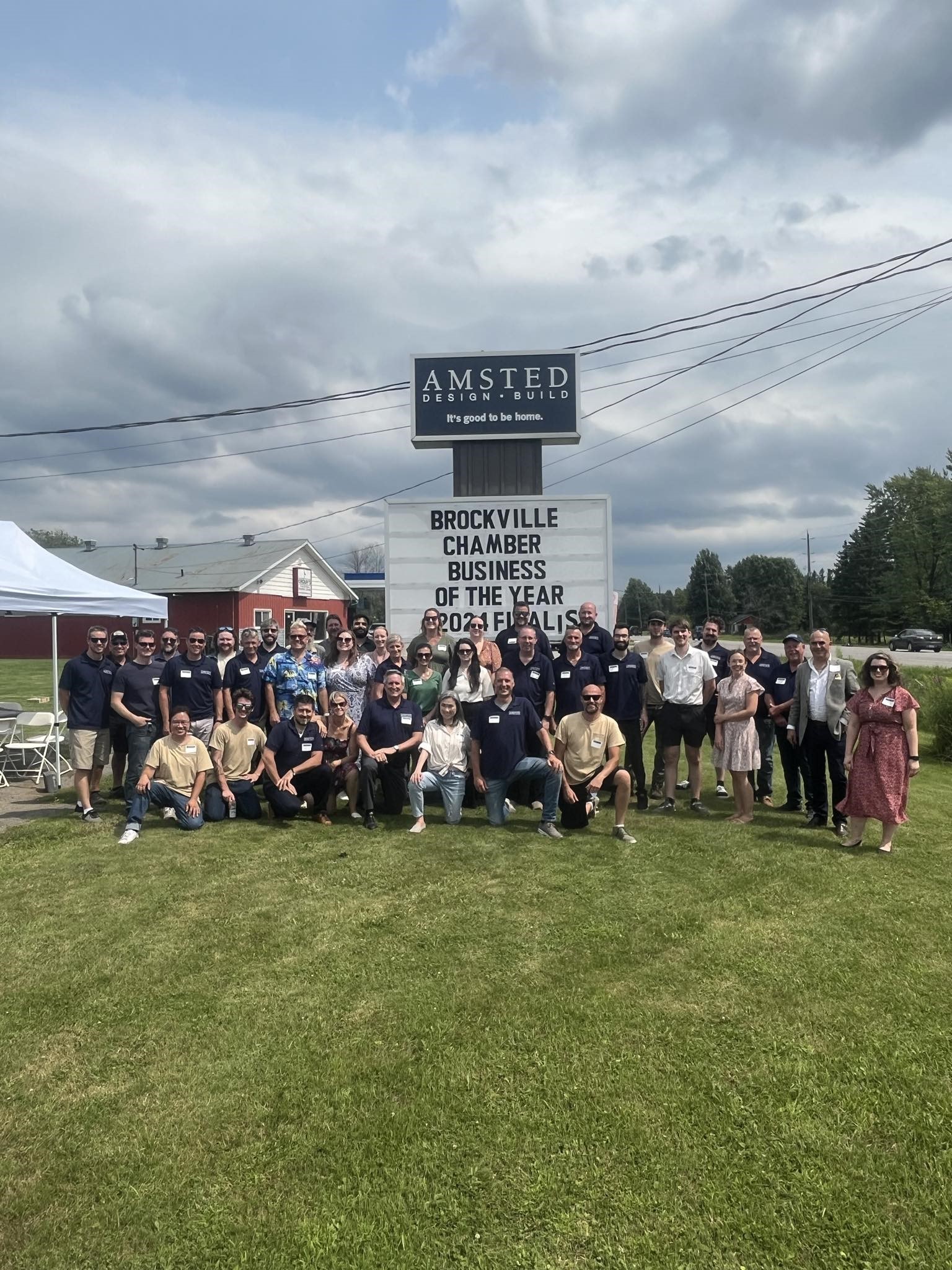 A group of people stands together for a photo in front of the "Amsted Chamber Finalist" sign, highlighting their collective accomplishment.
